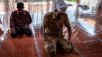 Jamaah Thoriqoh Qodriyah Naqsabandiyah menunaikan shalat zuhur berjamaah di antara sekat plastik.