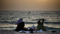 Sebuah keluarga Palestina menanti waktu berbuka puasa sambil menikmati detik-detik matahari tenggelam di pantai Kota Gaza.