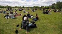 Sebagian mereka duduk bersantai di taman dengan tetap menjaga jarak sosial, namun banyak juga sebagian lainnya yang melanggar aturan social distancing. AP Photo/Kirsty Wigglesworth.