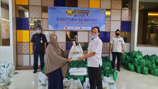 Rudi Pudianto selaku Manager Program Kemitraan dan Bina Lingkungan Brantas Abipraya (kanan depan) sedang menyerahkan bantuan sembako kepada perwakilan salah satu warga di sekitar Cawang. (Dok: Brantas Abipraya)