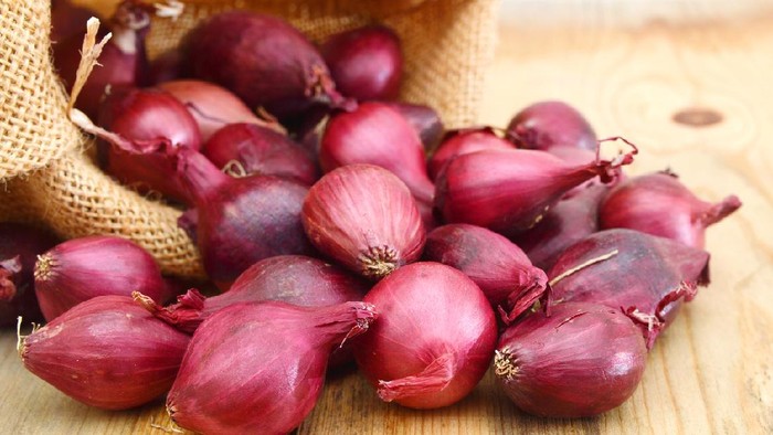 Red onions isolated in burlap on wooden background