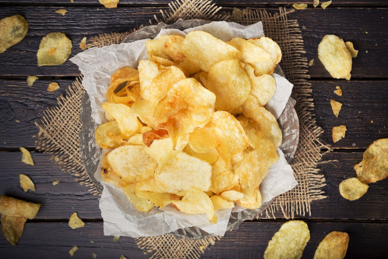 A bowl of potato chips on a rustic table.