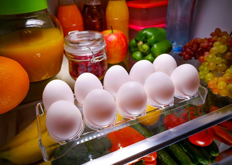 Cute female taking eggs from the fridge, attractive housewife take care about health, fresh tasty organic food, healthy eating concept