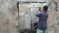 Seorang warga nampak memotret rumah yang telah hangus dilalap api. 