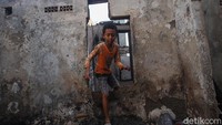 Seorang anak melintas melalui jendela rumah yang hangus terbakar.  