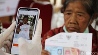 Warga difoto menggunakan smartphone oleh petugas kantor pos usai mendapatkan Bantuan Sosial Tunai 