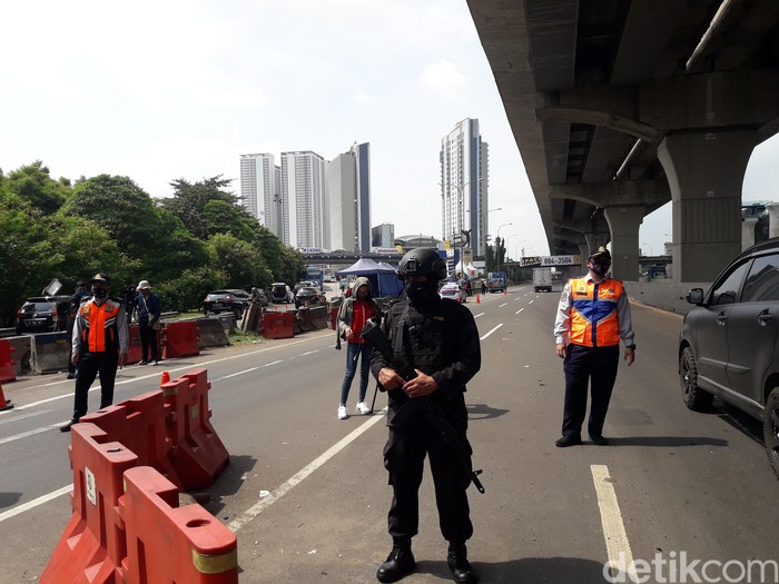 Seorang anggota Brimob bersenjata laras panjang disiagakan di check point gerbang tol (GT) Cikarang Barat untuk membantu mencegah keluarnya pemudik dari Jakarta di masa pembatasan sosial berskala besar (PSBB).