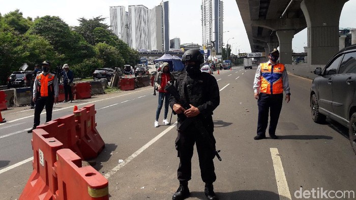 Seorang anggota Brimob bersenjata laras panjang disiagakan di check point gerbang tol (GT) Cikarang Barat untuk membantu mencegah keluarnya pemudik dari Jakarta di masa pembatasan sosial berskala besar (PSBB).