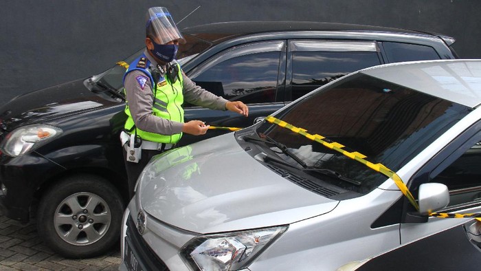 Polisi memasang garis polisi pada mobil travel ilegal yang ditahan di pos pemeriksaan Pembatasan Sosial Berskala besar (PSBB) Balearjosari, Malang, Jawa Timur, Jumat (22/5/2020). Sebanyak empat unit mobil travel ilegal yang mengangkut penumpang dari Madura dan Surabaya tersebut ditahan karena melanggar larangan mudik dari pemerintah saat PSBB sedang dilaksanakan di kawasan Malang Raya sebagai upaya pencegahan penyebaran COVID-19. ANTARA FOTO/Ari Bowo Sucipto/pras.