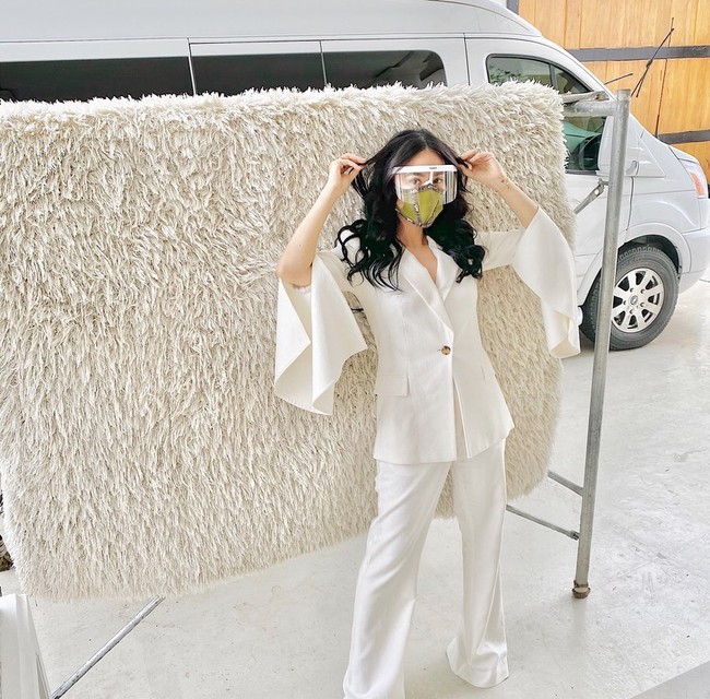 Pada gaya berikutnya, Heart Evangelista terlihat mengenakan setelan blazer putih dengan aksen flare pada lengan. Dia juga memakai face shield dan masker Hermes yang dibuatnya sendiri. Foto: Instagram/@iamhearte