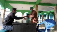 Seorang warga tengah membayar zakat fitrah kepada pengurus Masjid Jami Al Maghfiroh yang berada di Jalan Jati Waringin, Kota Bekasi, Jumat (22/5/2020). Ini merupakan salah satu masjid yang bakal gelar salat idul fitri.