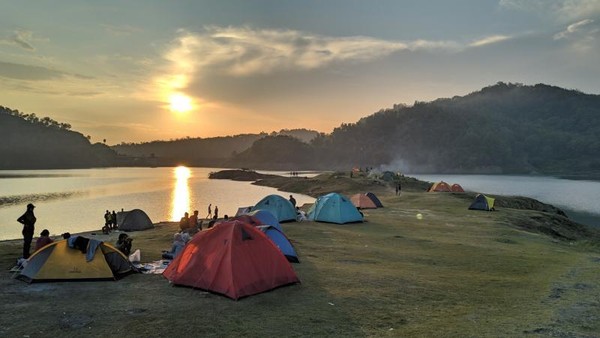 Pemandangan indah Waduk Sermo dengan air yang tenang dan dikelilingi perbukitan hijau