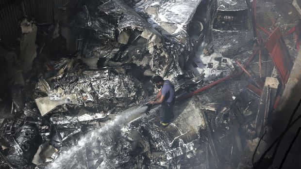 A firefighter tries to put out fire caused by plane crash in Karachi, Pakistan, Friday, May 22, 2020. An aviation official says a passenger plane belonging to state-run Pakistan International Airlines carrying more than 100 passengers and crew has crashed near the southern port city of Karachi. There were no immediate reports on the number of casualties. (AP Photo/Fareed Khan)