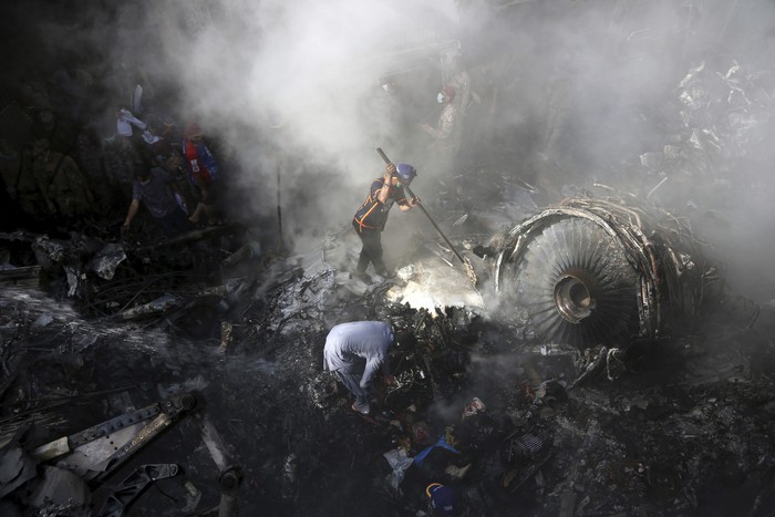 CORRECTS NUMBER OF PASSENGERS TO NEARLY 100, INSTEAD OF MORE THAN 100 - Volunteers look for survivors of a plane that crashed in a residential area of Karachi, Pakistan, May 22, 2020. An aviation official says a passenger plane belonging to state-run Pakistan International Airlines carrying nearly 100 passengers and crew crashed near Karachis airport. (AP Photo/Fareed Khan)