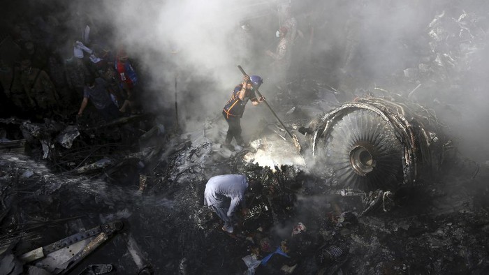CORRECTS NUMBER OF PASSENGERS TO NEARLY 100, INSTEAD OF MORE THAN 100 - Volunteers look for survivors of a plane that crashed in a residential area of Karachi, Pakistan, May 22, 2020. An aviation official says a passenger plane belonging to state-run Pakistan International Airlines carrying nearly 100 passengers and crew crashed near Karachis airport. (AP Photo/Fareed Khan)
