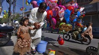 Seorang ayah membelikan putrinya sebuah balon berbentuk karakter animasi saat merayakan Hari Raya Idul Fitri 1441 Hijriah di kawasan Rawalpindi, Pakistan, Minggu (24/5/2020). AP Photo/Anjum Naveed.