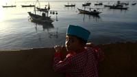 Seorang anak mengamati perahu yang bersandar usai menunaikan Shalat Idul Fitri 1441 H di Masjid AL-Mabrur, Kenjeran, Surabaya, Jawa Timur, Minggu (24/5/2020). ANTARA FOTO/Zabur Karuru.