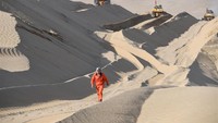 Pekerja Li Mingyou berjalan di atas bukit pasir di lokasi pembangunan jalan raya di Gurun Taklimakan, barat laut Daerah Otonomi Uygur Xinjiang. Foto: Dok. Xinhua/Hu Huhu