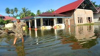 Warga berjalan melintasi banjir rob.
