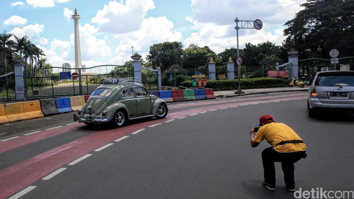 Pengunjung berfoto Dari balik Pagar Monumen Nasional, Jakarta, Senin (25/5/2020). PSBB Corona membuat tempat wisata ditutup untuk umum.