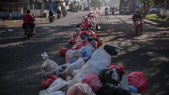 Pengendara melintas di dekat sampah yang menumpuk di pembatas jalan di Ciledug, Tangerang, Banten, Senin (25/5/2020). Wilayah tersebut sempat dipenuhi sampah rumah tangga yang tidak terurus karena libur lebaran. ANTARA FOTO/Rivan Awal Lingga/wsj.