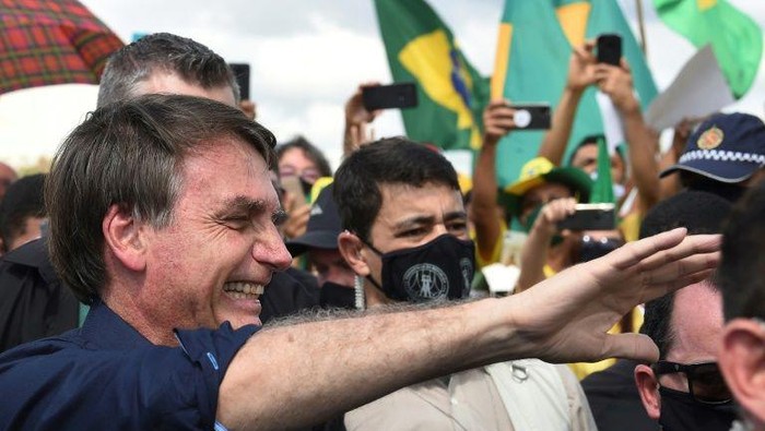 Presiden Brasil Jair Bolsonaro turun ke jalan sembari buang masker pada 24 Mei 2020 (AFP Photo)