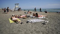 Turis Prancis terlihat bersantai di Pantai Grande Motte yang terletak di kawasan Laut Mediterania pada hari Minggu lalu. Mereka tampak berenang dan berjemur sembari saling menjaga jarak satu sama lain. (Foto: AP)