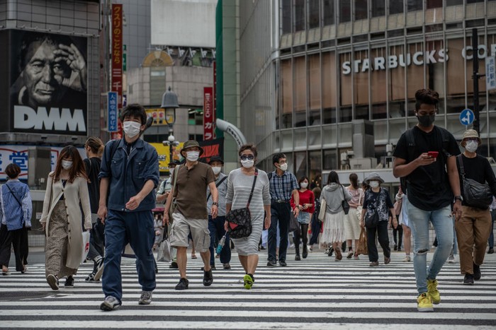 TOKYO, JAPAN - MAY 25: People, many wearing face masks, walk over Shibuya crossing on May 25, 2020 in Tokyo, Japan. As Covid-19 coronavirus cases in Japan continue to decline, Prime Minister Shinzo Abe today formally announced a complete end to the state of emergency that was imposed on April 7 in response to the outbreak. However, businesses around the country have been asked to implement social distancing and other protocols to avoid a second wave. To date, Japan has recorded 16,550 infections, 820 deaths and 13,413 recoveries from the virus. (Photo by Carl Court/Getty Images)