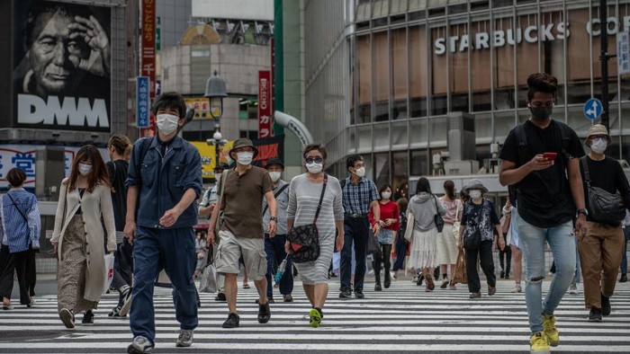 TOKYO, JAPAN - MAY 25: People, many wearing face masks, walk over Shibuya crossing on May 25, 2020 in Tokyo, Japan. As Covid-19 coronavirus cases in Japan continue to decline, Prime Minister Shinzo Abe today formally announced a complete end to the state of emergency that was imposed on April 7 in response to the outbreak. However, businesses around the country have been asked to implement social distancing and other protocols to avoid a second wave. To date, Japan has recorded 16,550 infections, 820 deaths and 13,413 recoveries from the virus. (Photo by Carl Court/Getty Images)