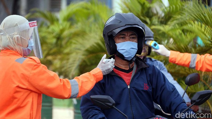 Petugas gabungan mengukur suhu tubuh para pengendara yang melintas di Jalan Raya Narogong KM16, Kota Bekasi. Ini bagian dari Operasi Ketupat Jaya 2020.