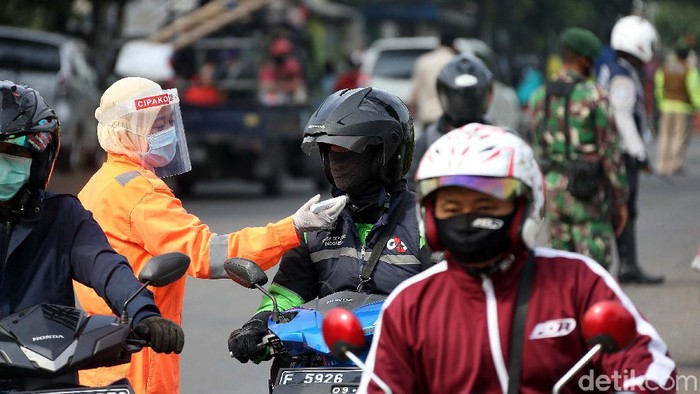 Petugas gabungan mengukur suhu tubuh para pengendara yang melintas di Jalan Raya Narogong KM16, Kota Bekasi. Ini bagian dari Operasi Ketupat Jaya 2020.