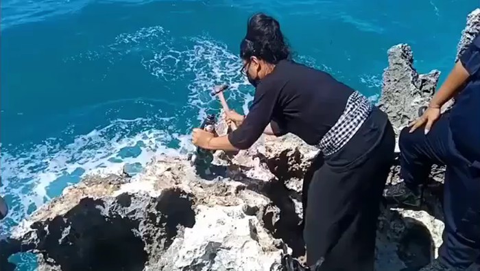 Pemasang melepas patung Nyi Roro Kidul yang terpasang di atas karang Pantai Waterblow Nusa Dua Bali (Screenshot video viral)