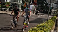 Dua warga bersepeda di jalanan Jakarta yang masih sepi.
