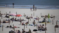 Jaga jarak sosial (social distancing) di pantai itu diatur dengan menancapkan tiang kayu yang tiap sudutnya dihubungkan menggunakan tali. Pantai ini pun memiliki beberapa petak yang masing-masing seluas 8 meter persegi yang dapat dimanfaatkan setiap pengunjung. (Foto: AP)