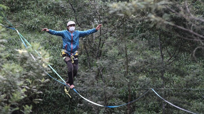 OLAHRAGA EKSTRIM HIGHLINE Highliner dan juga pemandu wisata ekstrim 'highline' Andi Ardi berlatih di hutan lereng Gunung Merapi, Balerante, Klaten, Jawa Tengah, Rabu (27/5/2020). Olahraga ekstrim 'highline' atau atraksi dengan cara berjalan di atas tali pipih yang diikat antara dua tebing tersebut menjadi potensi wisata minat khusus yang semakin diminati masyarakat. ANTARA FOTO/Hendra Nurdiyansyah/foc.