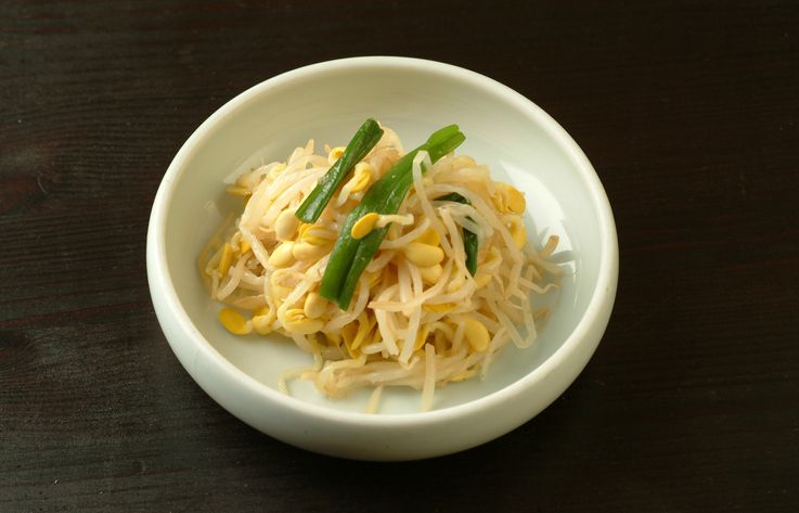 Slices of yellow pickled daikon radish served on a plate. A healthy accompaniment to Japanese and Korean foods.