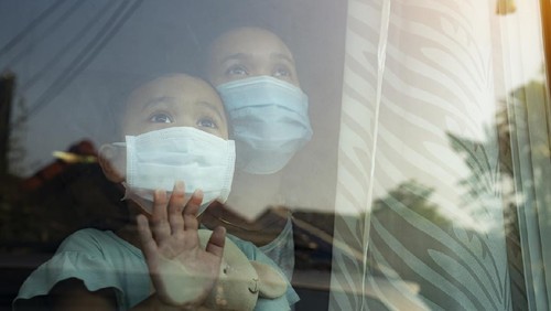 Stay at home quarantine coronavirus pandemic prevention.Mother and daughter in protective medical masks standing near on window and looks out window.
