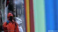 Petugas PPSU yang melakukan penyemprotan disinfektan tampak mengenakan alat pelindung diri seperti masker, pakaian khusus dan sarung tangan.