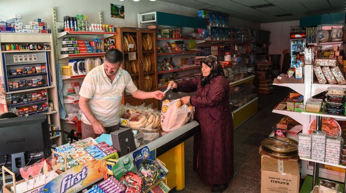Seorang wanita membeli roti di toko kelontong, Kalfat, Cankiri, Turki.