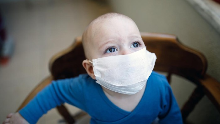 Ilustrasi bayi memakai masker A little boy puts a medical mask on his face.