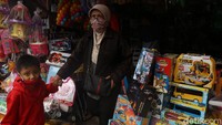 Seorang ibu membawa anaknya belanja mainan di Pasar Gembrong.