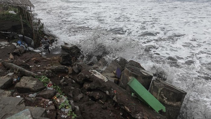 Seorang warga menghindari hempasan ombak saat mencoba memasang karung pasir di lokasi tanggul yang jebol, untuk menahan air laut agar tidak menggenangi pemukiman warga di Pantai Tegalkamulyan, Cilacap, Jawa Tengah, Rabu (27/5/2020). Gelombang tinggi air laut yang mencapai enam meter di pesisir selatan jawa tengah, menyebabkan tiga titik tanggul penahan rob di sepanjang pantai  TegalKamulyan jebol, dan memicu abrasi serta menyebabkan air rob menggenangi pemukiman warga, area persawahan dan tambak udang. ANTARA FOTO/Idhad Zakaria/foc.
