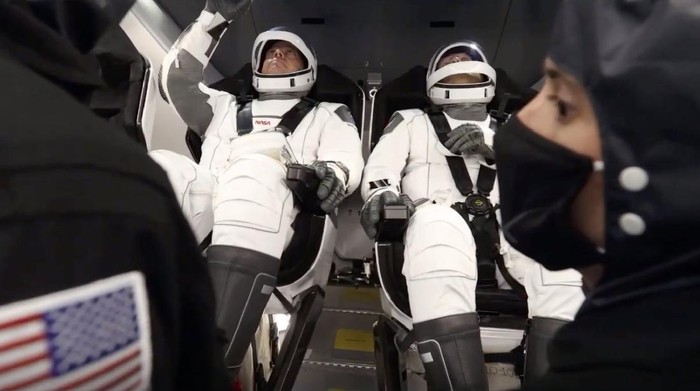 In this Wednesday, May 27, 2020 image from video made available by SpaceX, NASA astronauts Bob Behnken, background left, and Doug Hurley perform communication checks in the Crew Dragon capsule before launch from the Kennedy Space Center in Cape Canaveral, Fla. (SpaceX via AP)