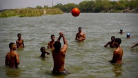 Sejumlah pemuda menyegarkan tubuh sambil bermain bersama kawan-kawannya di Sungai Yamuna yang berada di kawasan New Delhi, India, Kamis (28/5/2020). AP Photo/Manish Swarup.
