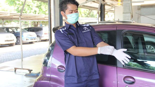Mekanik Astra Peugeot menggunakan masker dan sarung tangan saat bekerja