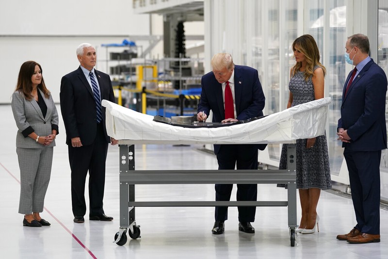 President Donald Trump signs a piece of equipment as he and first lady Melania Trump participate in a tour of NASA facilities before viewing the SpaceX Demonstration Mission 2 Launch at Kennedy Space Center, Wednesday, May 27, 2020, in Cape Canaveral, Fla. Vice President Mike Pence, second from left, second lady Karen Pence, left, and NASA Administrator Jim Bridenstine look on. (AP Photo/Evan Vucci)