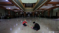 Dua petugas memasang tanda khusus berbentuk silang di dalam masjid.
