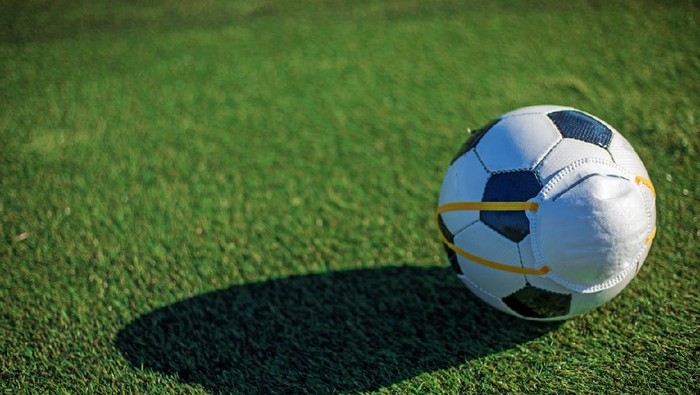 Ilustrasi bola, ilustrasi bola new normal Soccer ball and virus mask to symbolise the delayed, postponed and cancelled Soccer and football competitions due to the corona Covid-19 virus outbreak