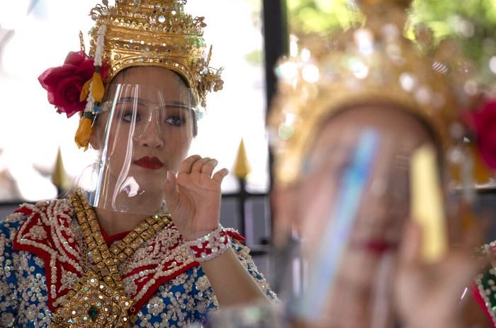 Penari menampilkan tarian tradisional Thailand dengan gunakan face shield. Meski lockdown dilonggarkan, Warga Thailand diimbau untuk patuhi protokol kesehatan.