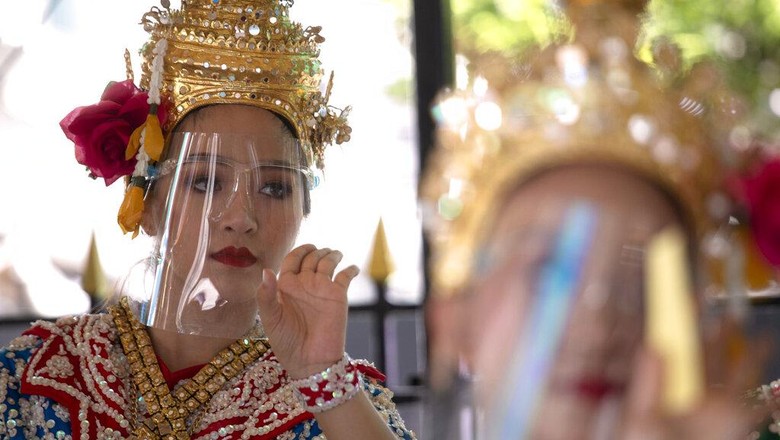 Penari menampilkan tarian tradisional Thailand dengan gunakan face shield. Meski lockdown dilonggarkan, Warga Thailand diimbau untuk patuhi protokol kesehatan.